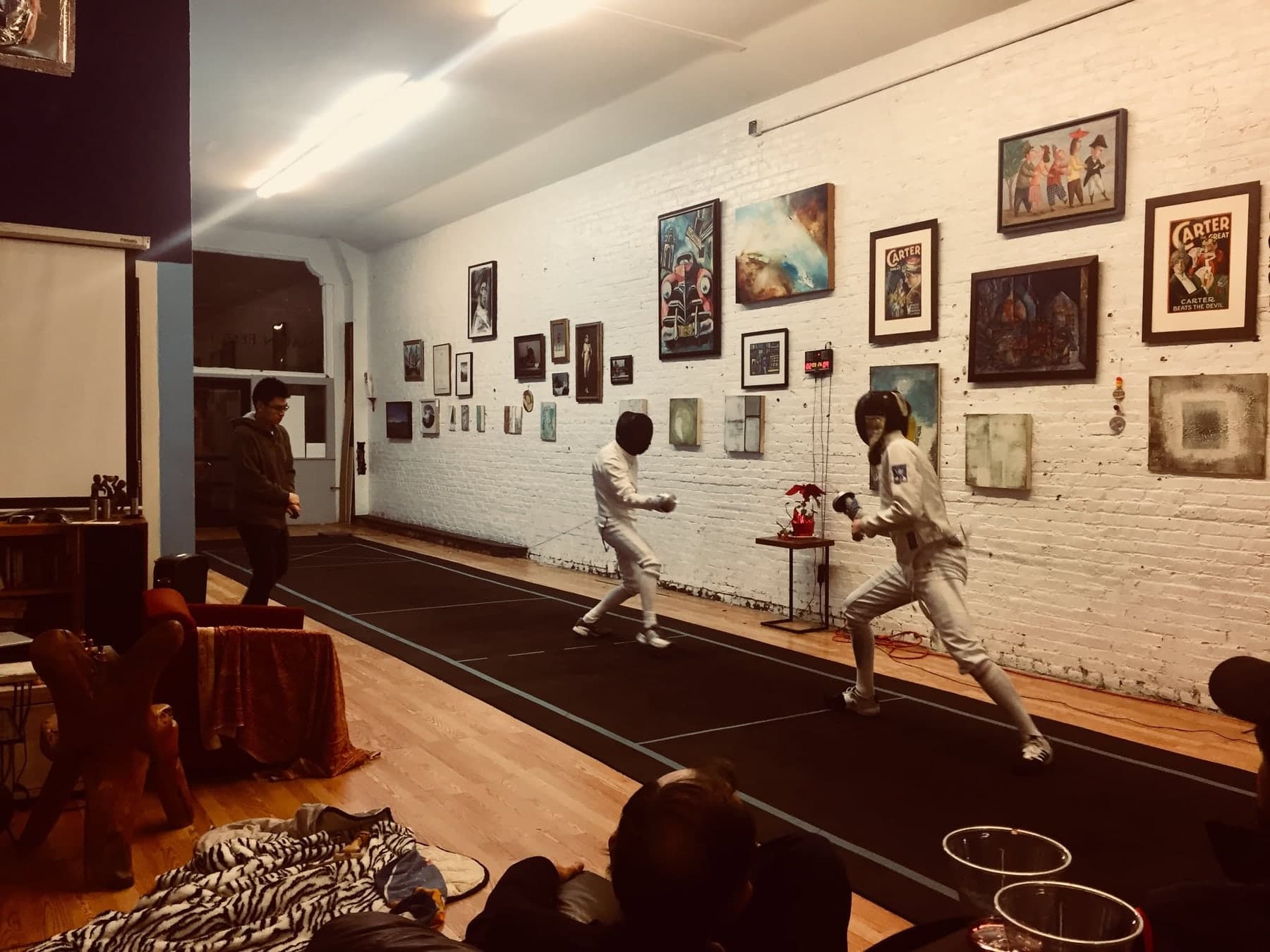 Marin Fencing Academy — A bout under way along the salle's brick wall of framed fencing prints