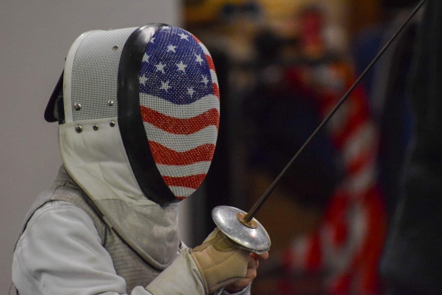 A fencer in a stars-and-stripes mask holding a foil