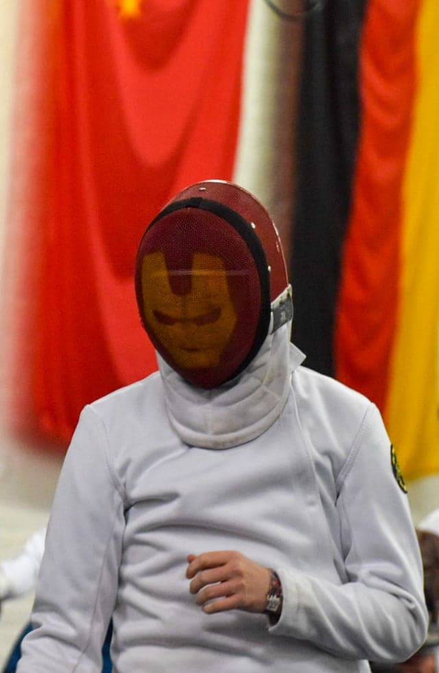A fencer in a red mask between bouts